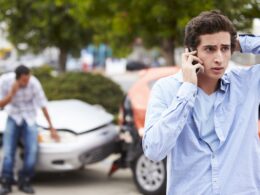 young man on talking on his cell phone after being involved in a car accident