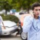 young man on talking on his cell phone after being involved in a car accident