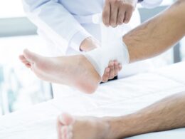 Photo of a physician placing a bandage on a patients ankle