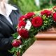 photo of a woman placing red roses on top of a funeral casket