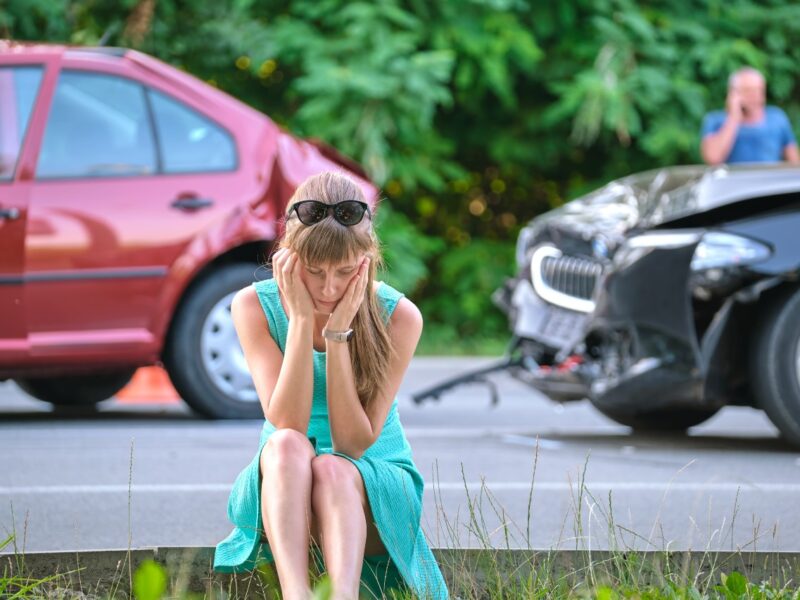photo of a sad woman at the scene of a car accident