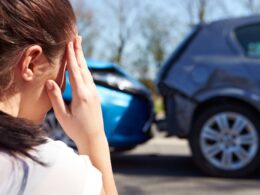 woman touching her head at a car accident scene