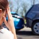 woman touching her head at a car accident scene